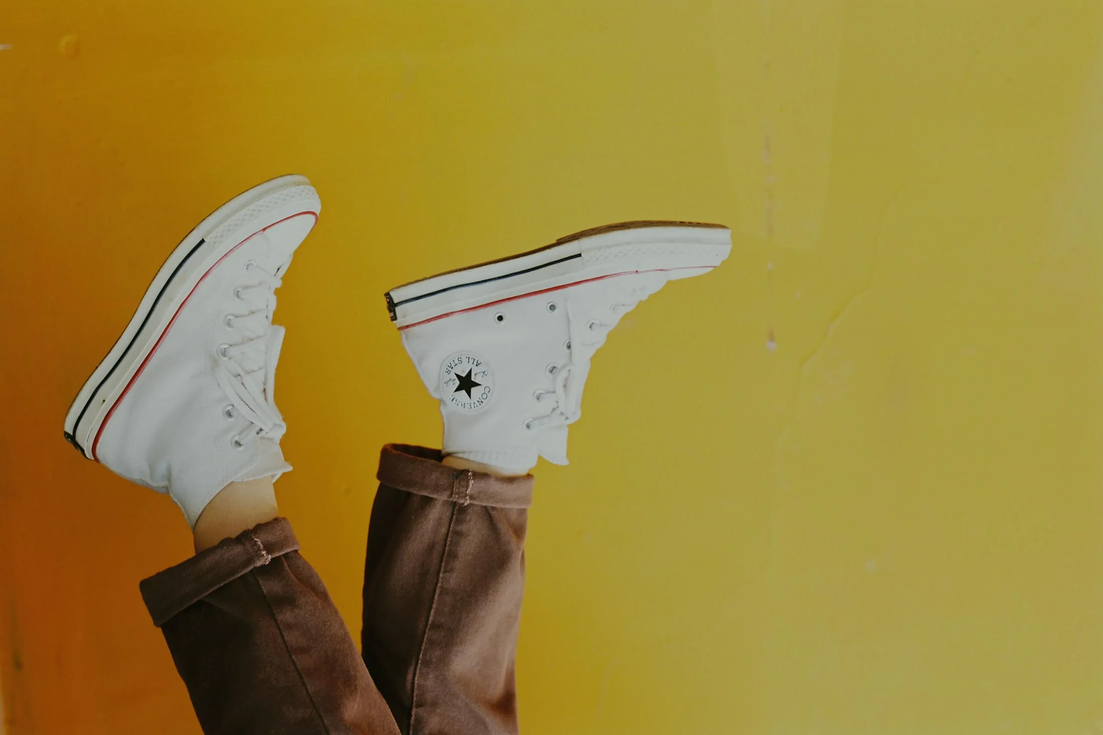 White sneakers against a bright yellow background
