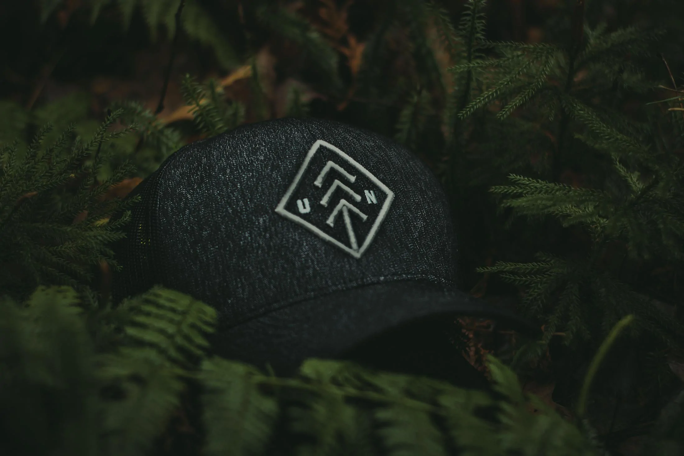 Cap with a logo resting on a mossy forest floor